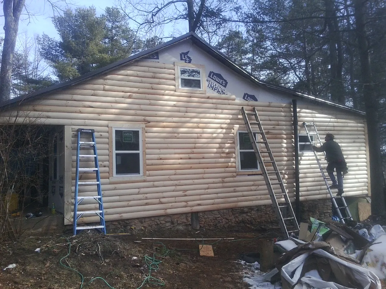 Ladders set against fresh log siding during an exterior remodel in Orange