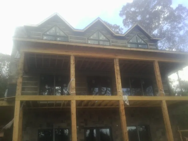Dormers and porch framing on a large log home under construction — Roof Coating work by our crew in Orange