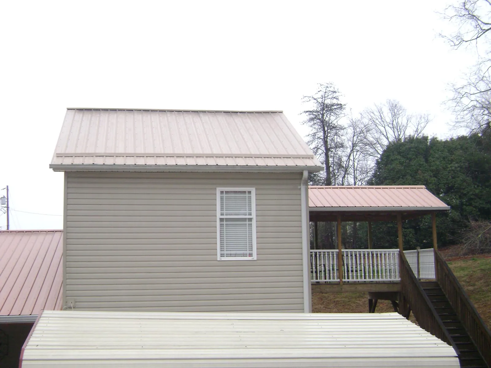 Tan metal roofs on a two story addition and attached porch, from a Roof Replacement job in Orange